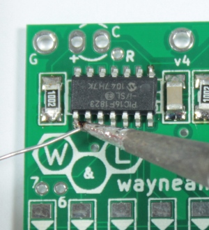 Tack the chip in place by soldering a pin in the opposite corner