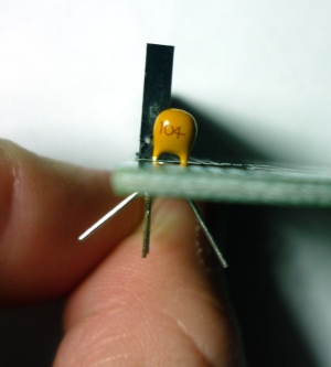 Bend the capacitor leads outwards to prevent it from falling out